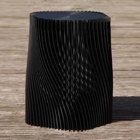 Schwarze Urne mit Rillenstruktur in Wellenform -...