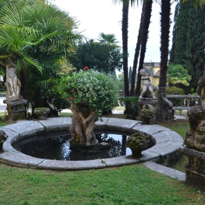 Brunnen umgeben von kleinen Figuren im Garten der Villa D’Annunzio © Serafinum.de