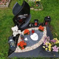 Kindergrab mit schwarzem Grabstein und liebevoller Deko