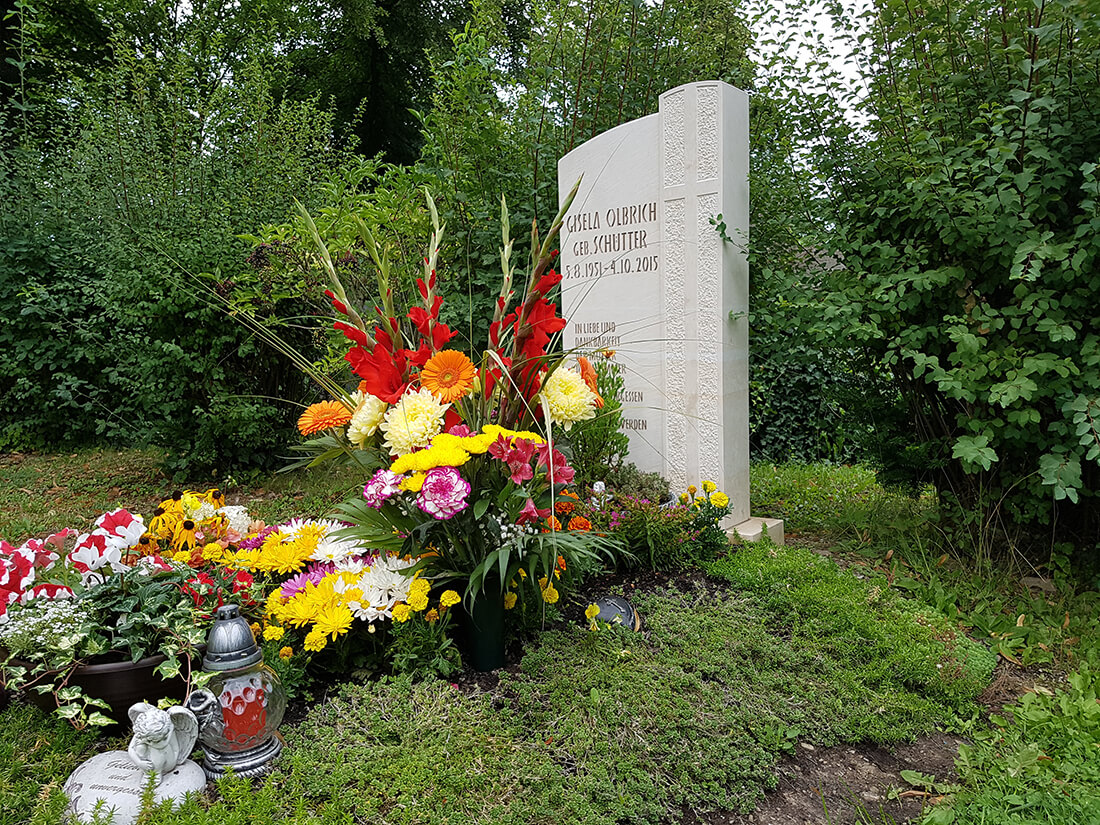 Eine üppige Grabbepflanzung hebt das Grab auf dem Friedhof hervor.