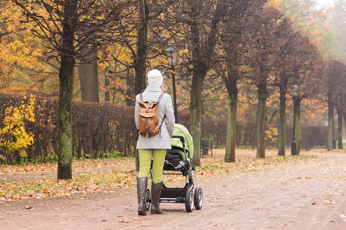 Alleinerziehende Mutter schiebt einen Kinderwagen