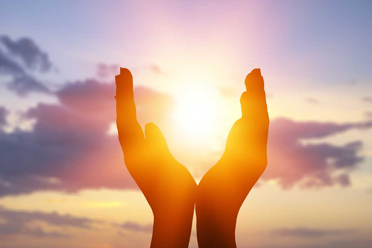 Hände vor Sonne am Himmel